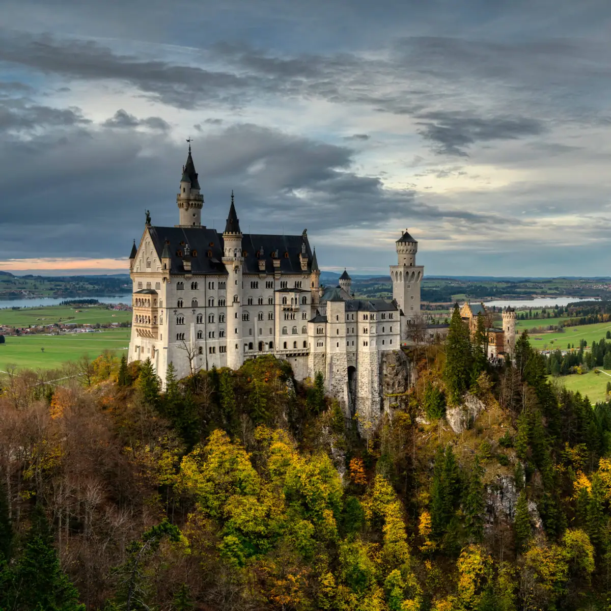 Kasteel Neuschwanstein Kasteel Neuschwanstein op een heuvel met herfstbomen op de voorgrond.