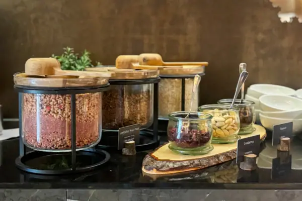 Een toonbank met verschillende soorten muesli in bakjes. Ernaast liggen noten en zaden.