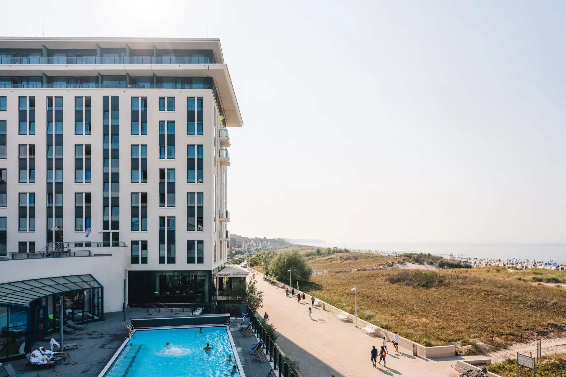 aja Warnemünde Een gebouw met een zwembad en mensen die voorbij lopen.