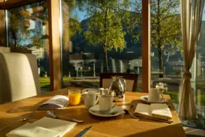 Ein Tisch mit einer Teekanne und Tassen vor einer Glaswand.