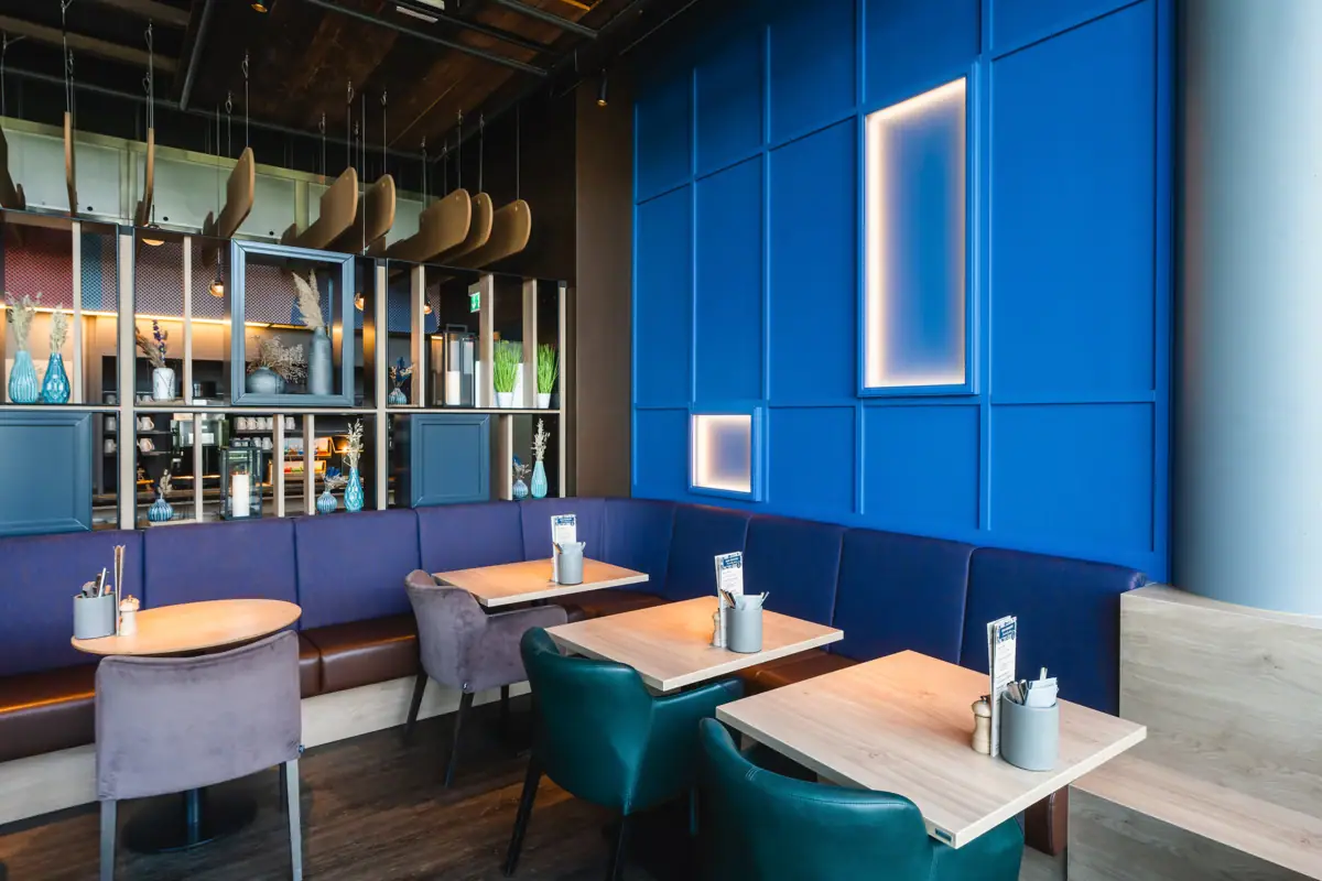 Restaurant bij aja Warnemünde Blauwe bank met tafels en stoelen in het restaurant.