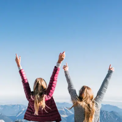 Zugspitze uitzicht Twee vrouwen staan op een berg met hun armen omhoog.