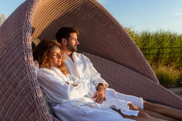 Een man en vrouw in badjassen zittend in een rieten stoel.