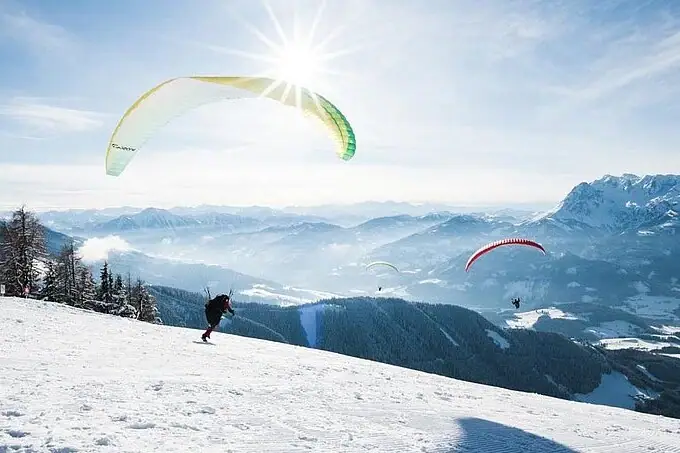 Groep mensen aan het paragliden op een besneeuwde berg.