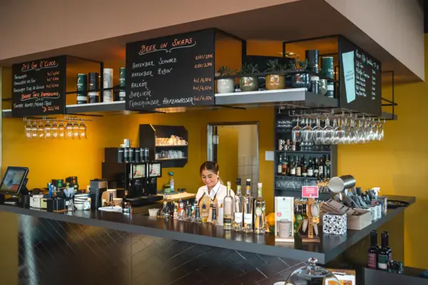 Vrouw achter een bar met flessen op de achtergrond