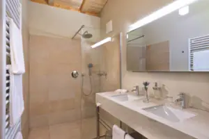 Een badkamer met douche en wastafel.
