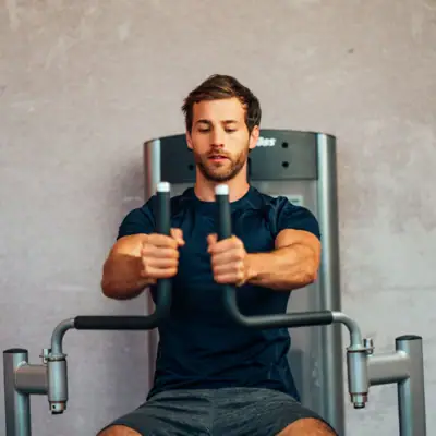 Een man traint op een fitnessapparaat.