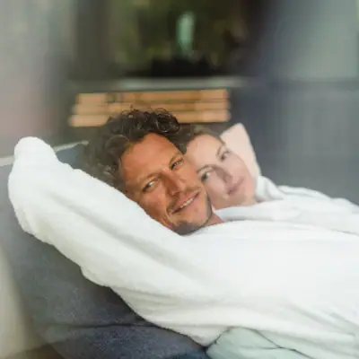 Een man en een vrouw liggen comfortabel op een bank.