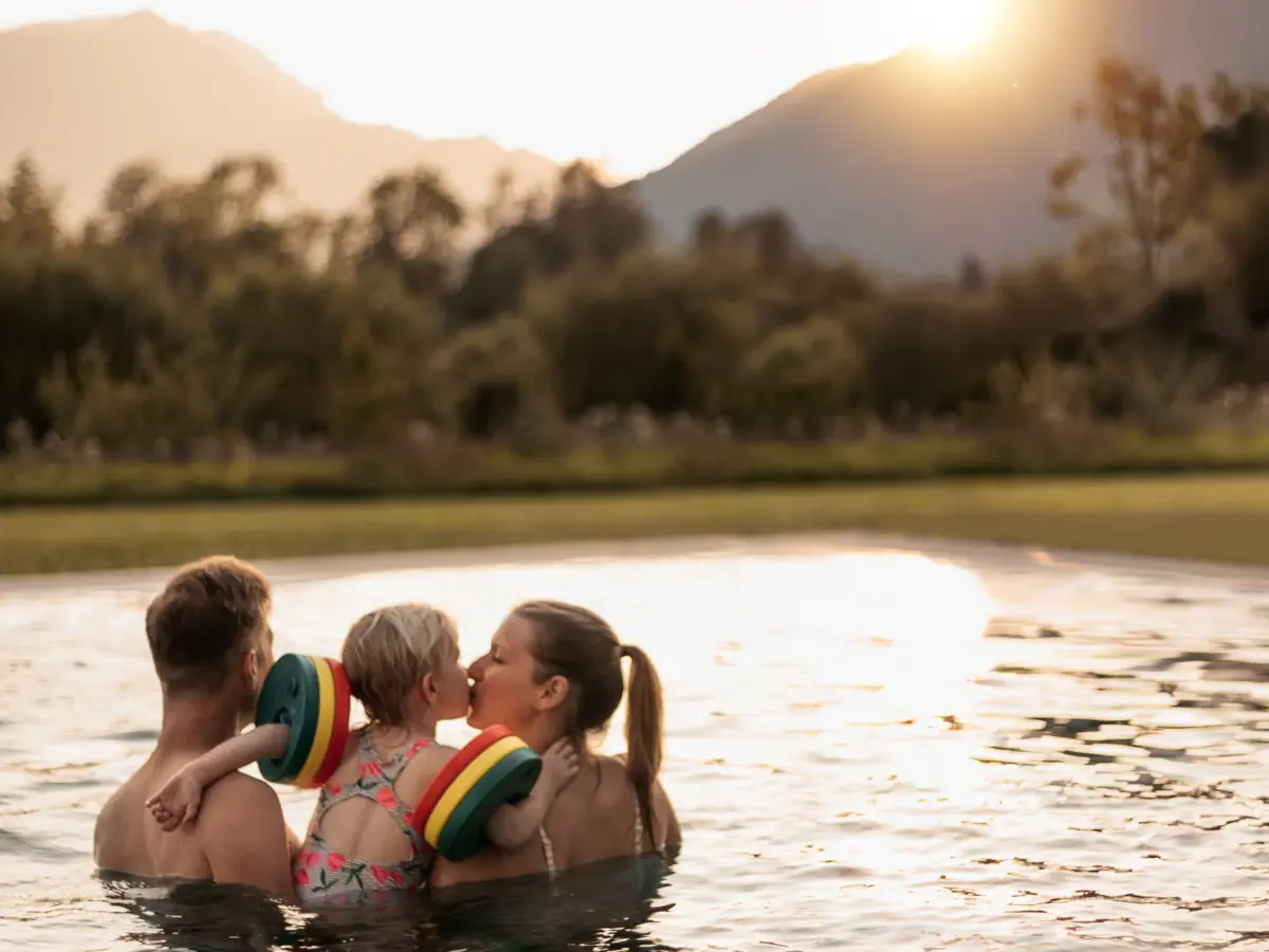 Ouders met een kind in het aja-familiehotel in Ruhpolding, Beieren, die in het buitenzwembad zwemmen.