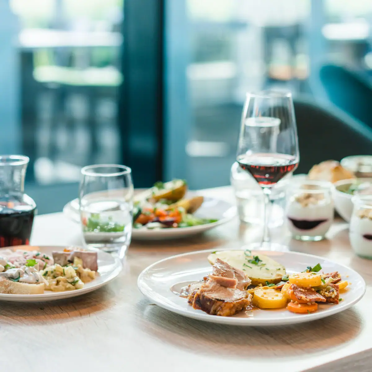 Een tafel met borden vol eten en glazen wijn.