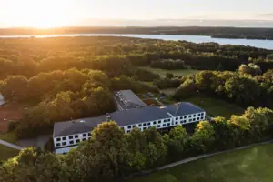 Ein Gebäude umgeben von Bäumen und einem Gewässer.