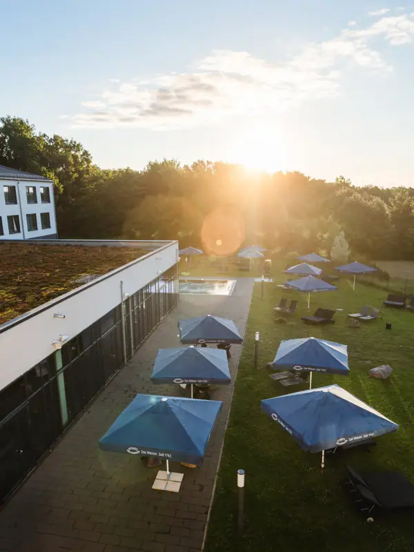 aja Bad Saarow Een gebouw met parasols en stoelen op een grasveld.