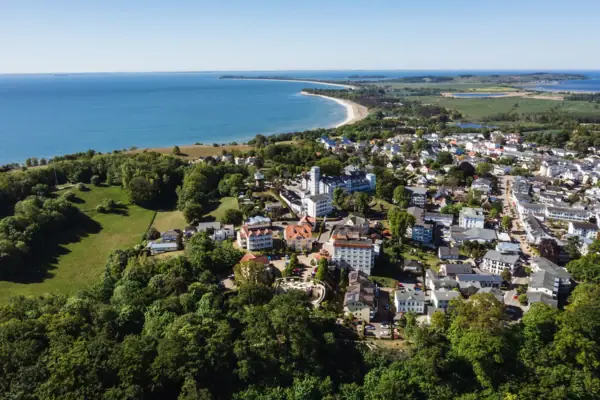 Luchtfoto van een stad aan het water met huizen en bomen.
