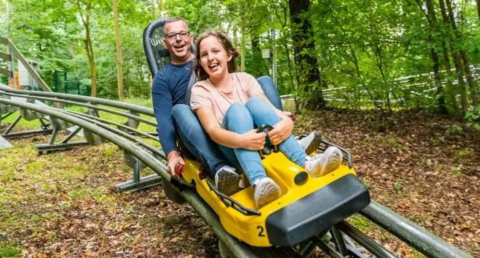 Een man en een vrouw in een achtbaan, allebei lachend.