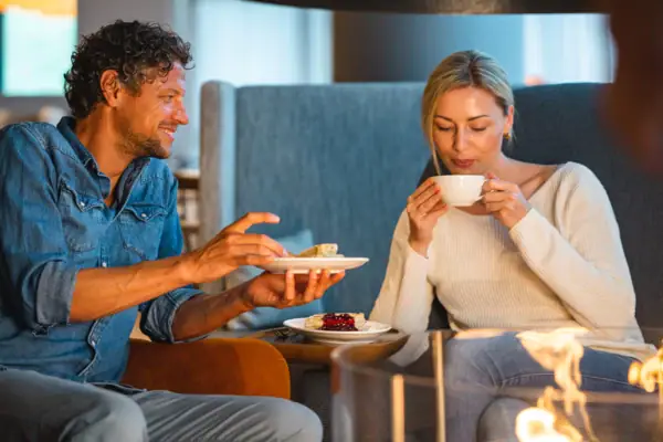 Een man en een vrouw zitten op een bank bij de open haard en eten.