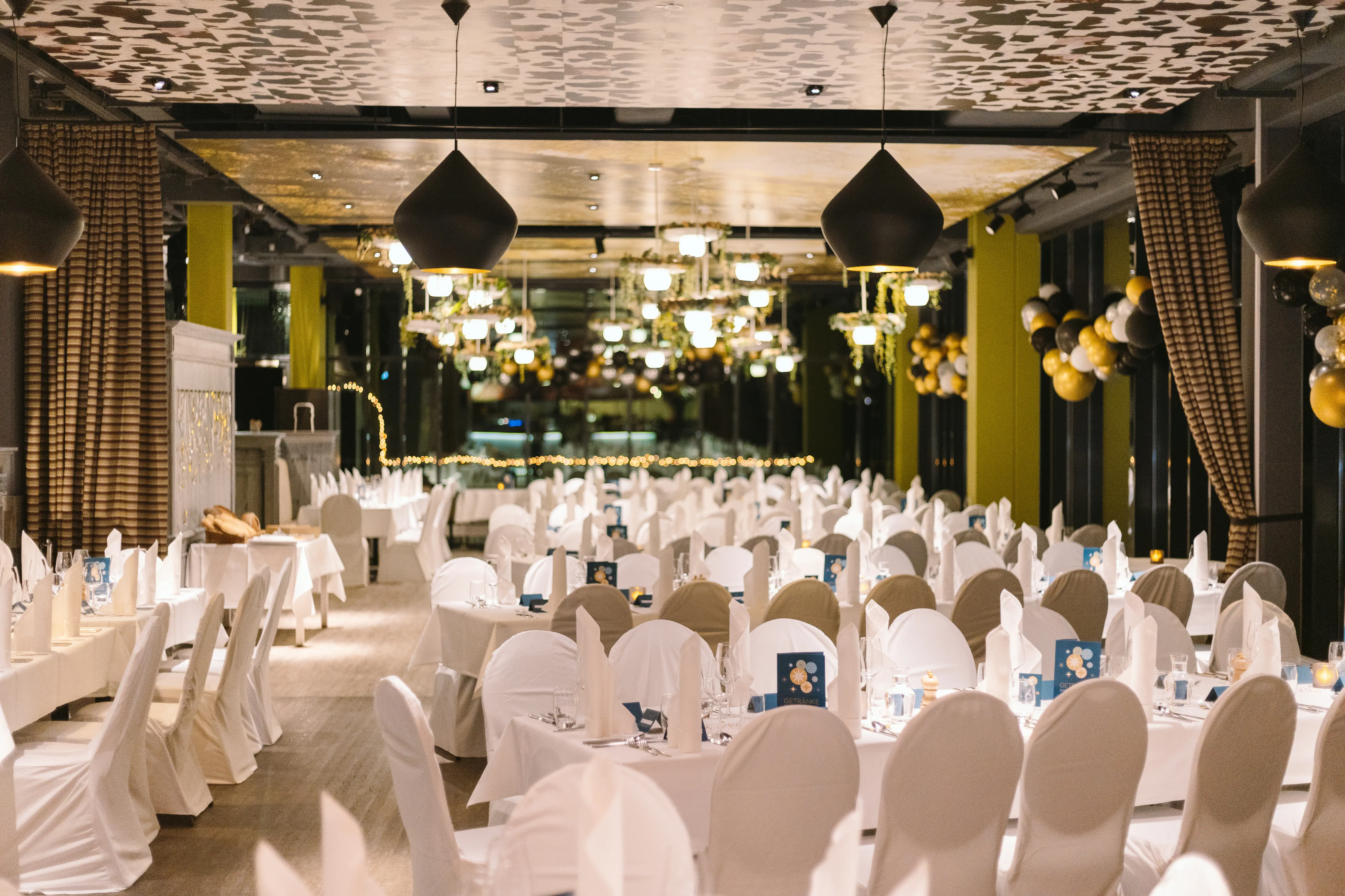 Het restaurant van aja Bad Saarow is feestelijk versierd. Verschillende tafels met witte tafelkleden en stoelhoezen. 