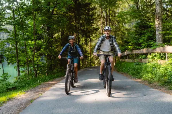 Een man en een vrouw fietsen over een pad met bomen.