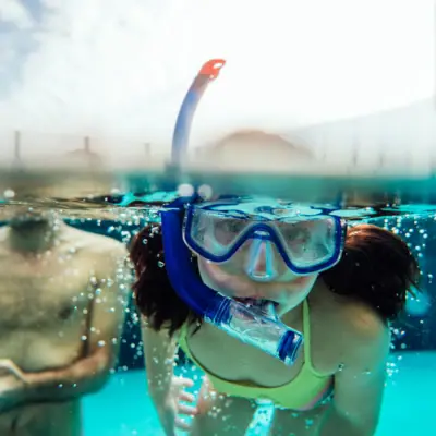 Zwemlessen Een meisje in zwempak en zwembril onder water.