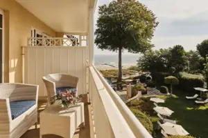 Balkon mit Stühlen, Tisch und der Ostsee im Hintergrund.