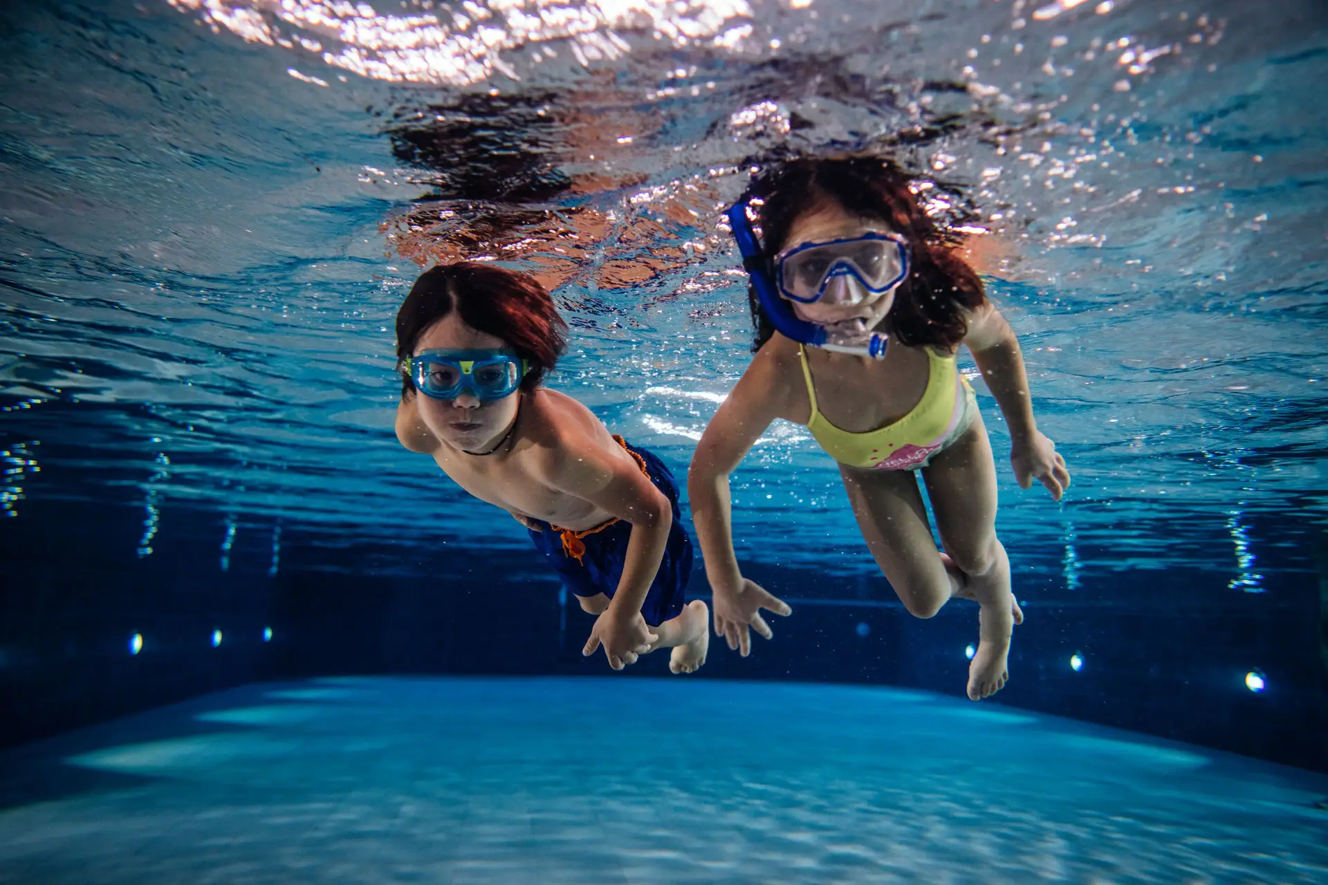 Kinderen duiken in het zwembad Verschillende mensen zwemmen onder water in het zwembad.