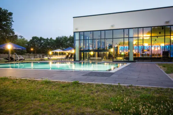 Een gebouw met zwembad en gazon.