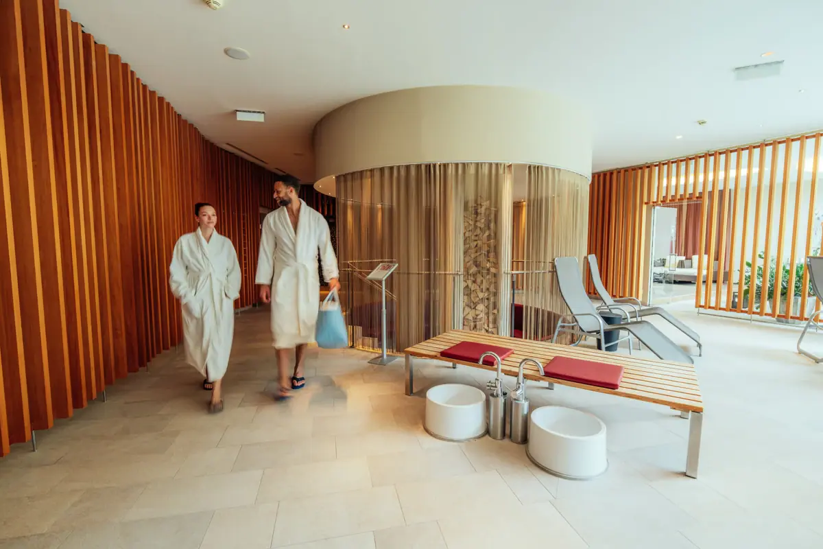 SPA-gedeelte Een man en een vrouw in witte badjassen lopen door een kamer.