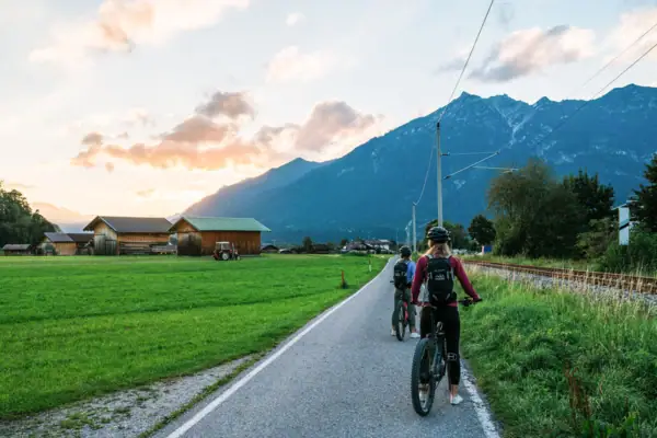 Fietsen Mensen op fietsen op een weg met gras en bergen op de achtergrond.
