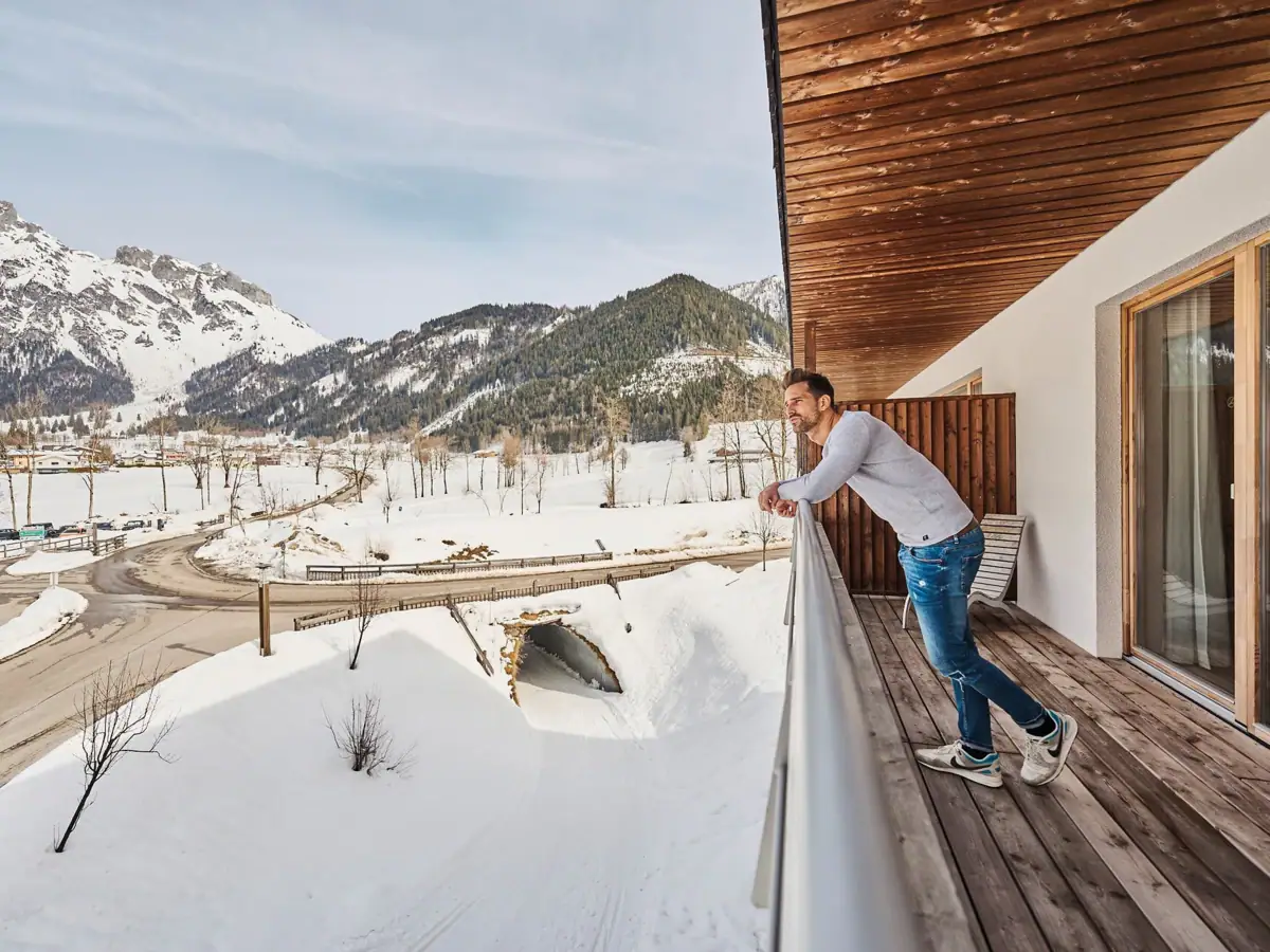 Een man staat op een besneeuwd balkon.