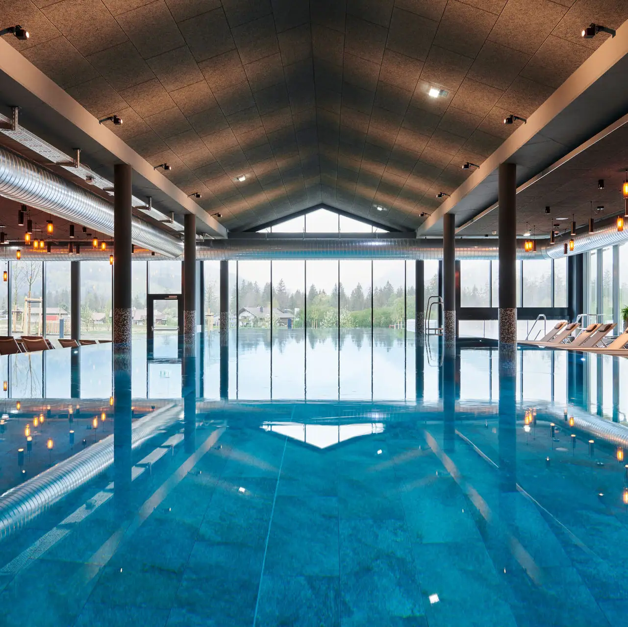 Groot binnenzwembad met hoge plafonds en grote ramen.