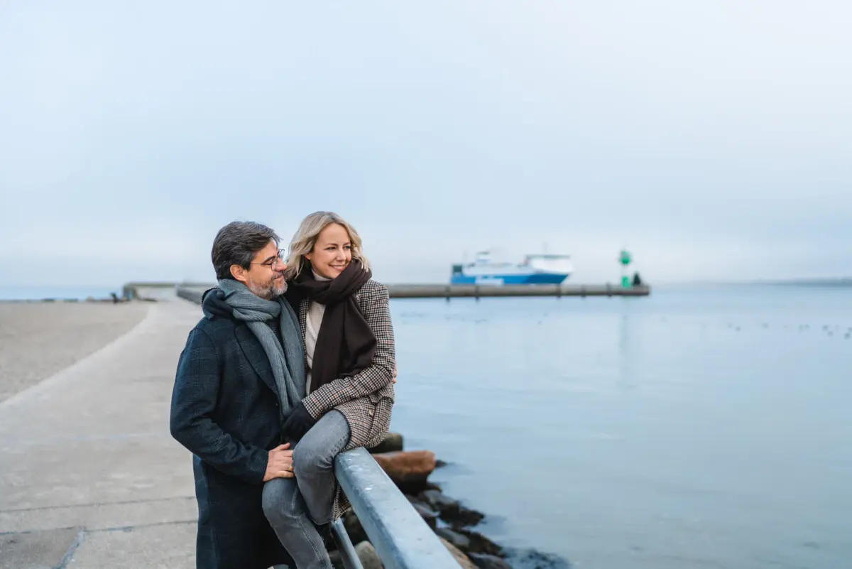 Travemünde Een man en een vrouw staan bij een reling aan het water.