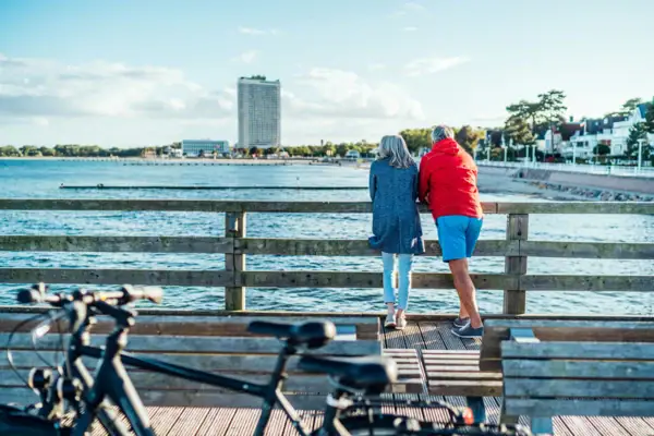 Een man en een vrouw staan op een houten brug en kijken uit over het water.