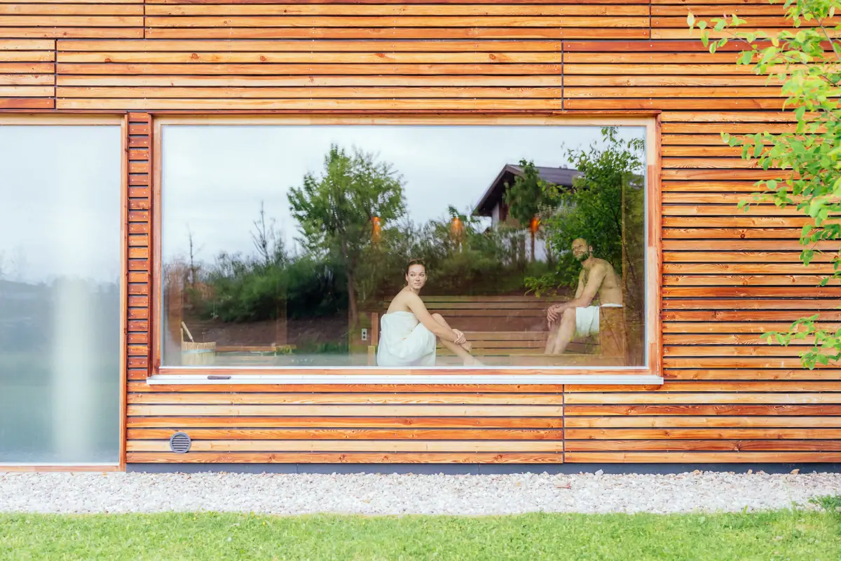 Sauna Een man en een vrouw zitten op een bankje in een houten huis.
