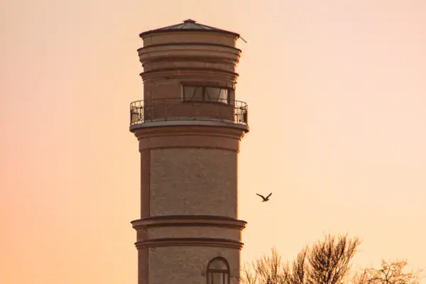Een vuurtoren met een vogel in de lucht.