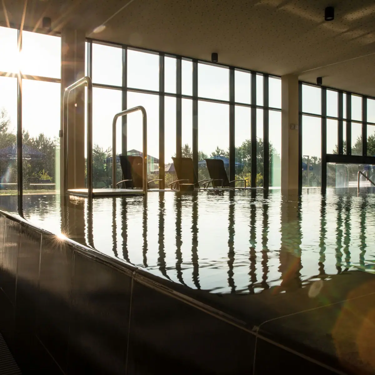 Contact & openingstijden Een zwembad met een groot raam en waterreflecties.