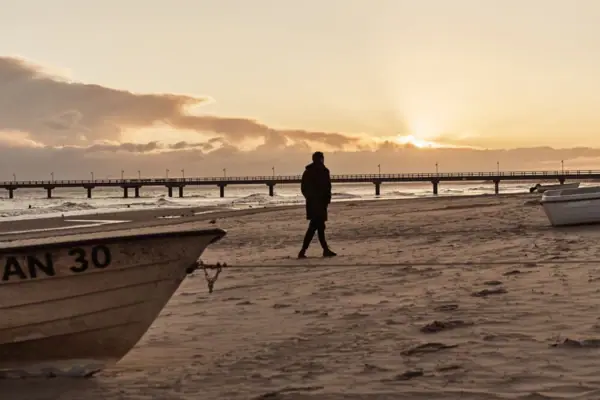 Een persoon loopt langs het strand.