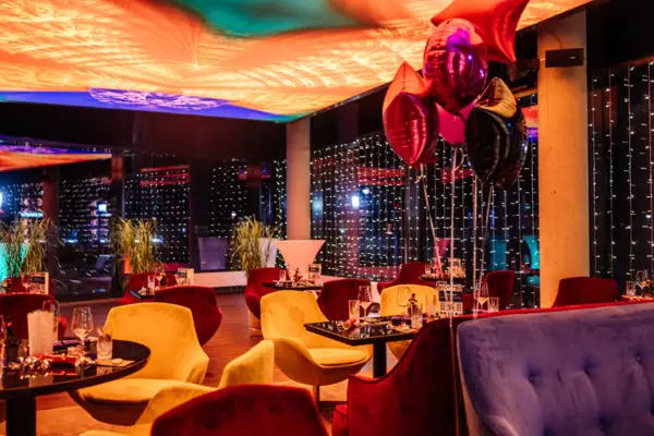 Een kamer met tafels, stoelen en ballonnen.