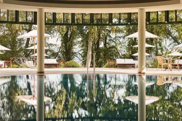 Een zwembad met parasols en stoelen op de achtergrond.