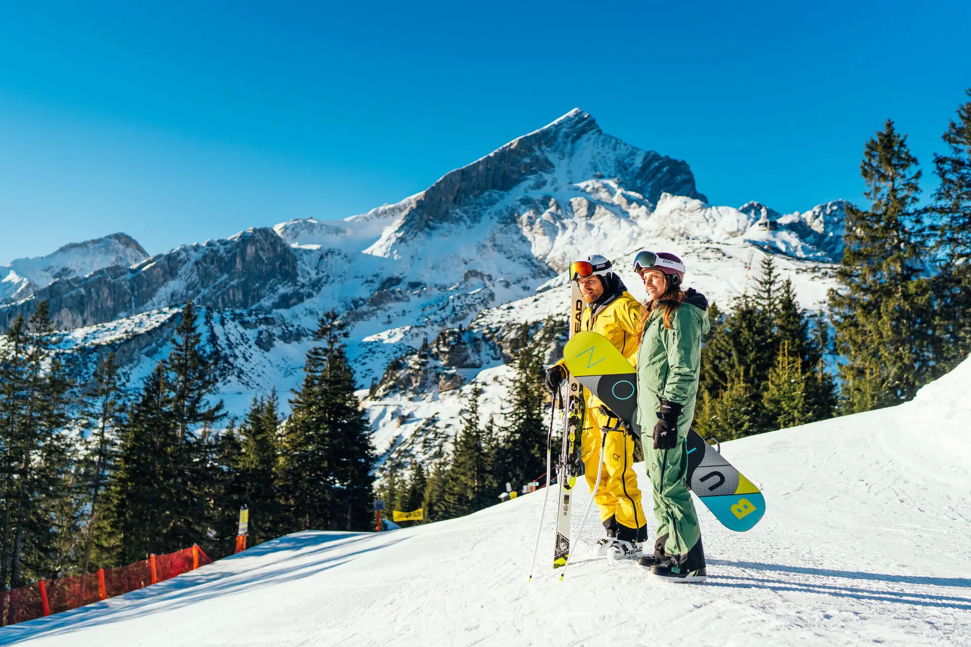 Wintersport Twee mensen in sneeuwkleding staan op een besneeuwde berg.