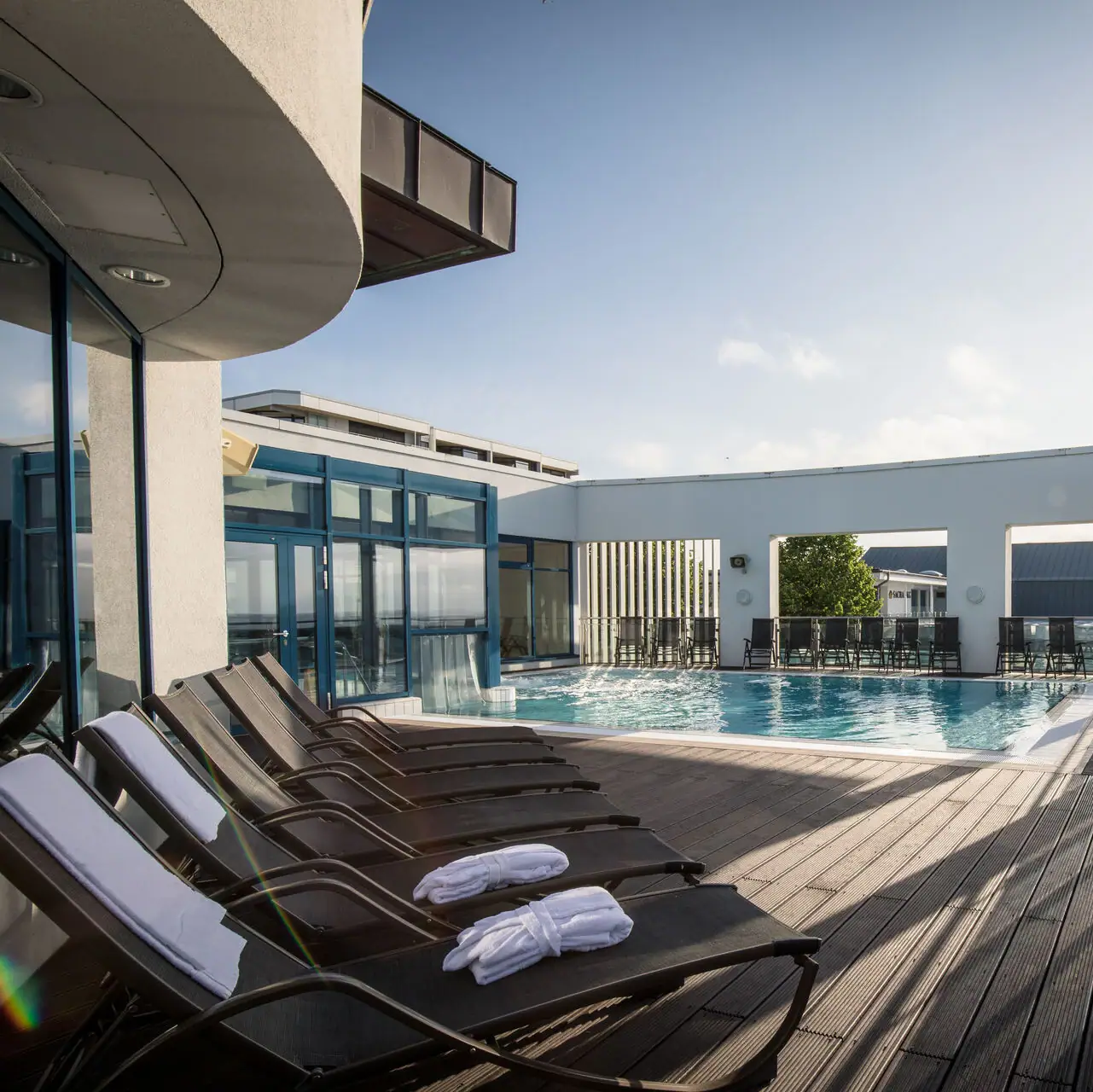 Buitenzwembad Grömitzer Welle Een zwembad met ligstoelen en een buitendek.