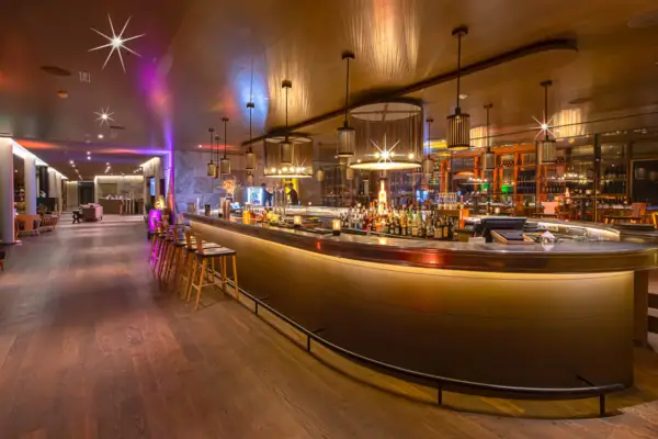 Een bar met een toonbank en krukken.