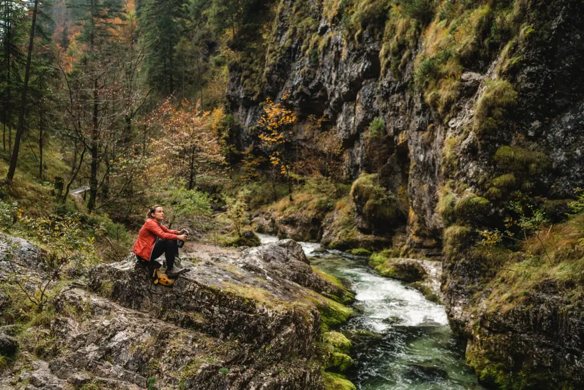 Wandelen bij Ruhpolding Een vrouw zit op een rots bij de rivier.