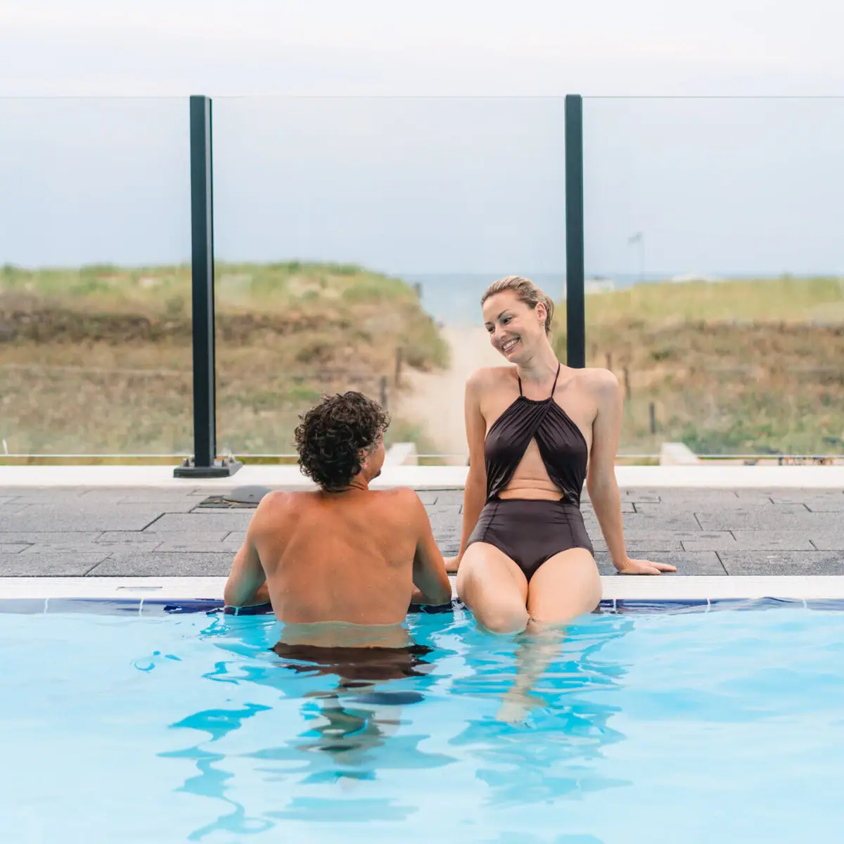 Een man en een vrouw zitten in een zwembad.