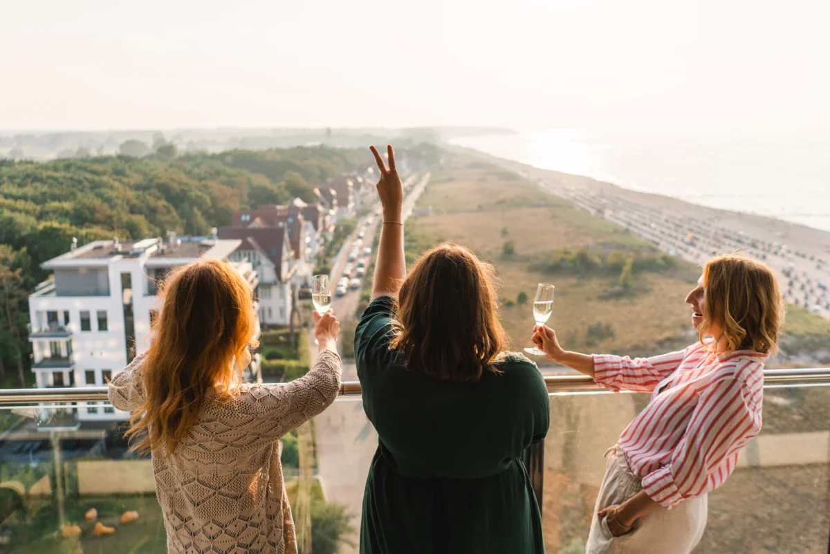 Uitzicht vanaf het balkon Een groep mensen houdt glazen wijn vast en staat op een balkon.