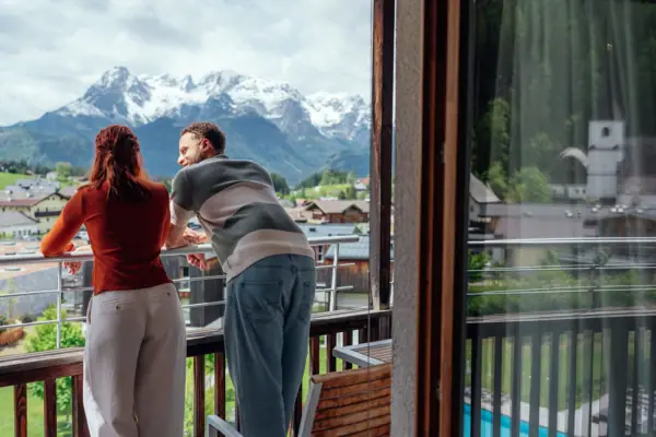 Kamer met balkon Een man en een vrouw staan op een balkon en kijken uit over de bergen.