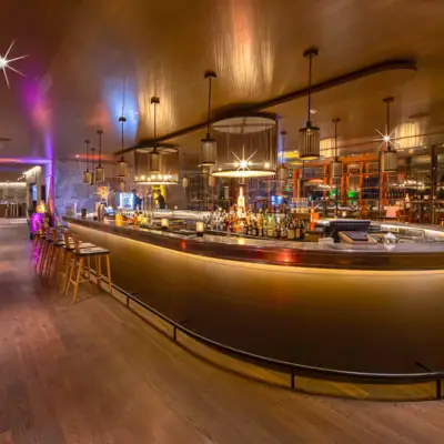 Een bar met een toonbank en krukken.