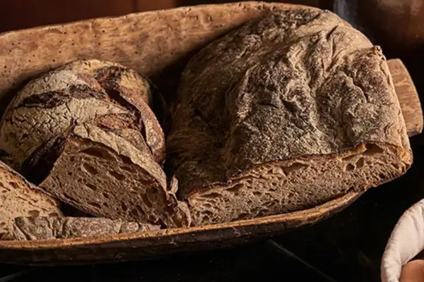 Een brood en eieren in een mandje naast een glas melk.