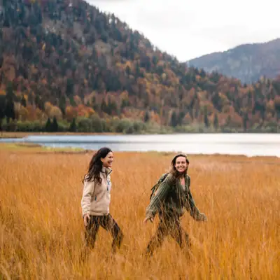 Twee vrouwen lopen door hoog gras.