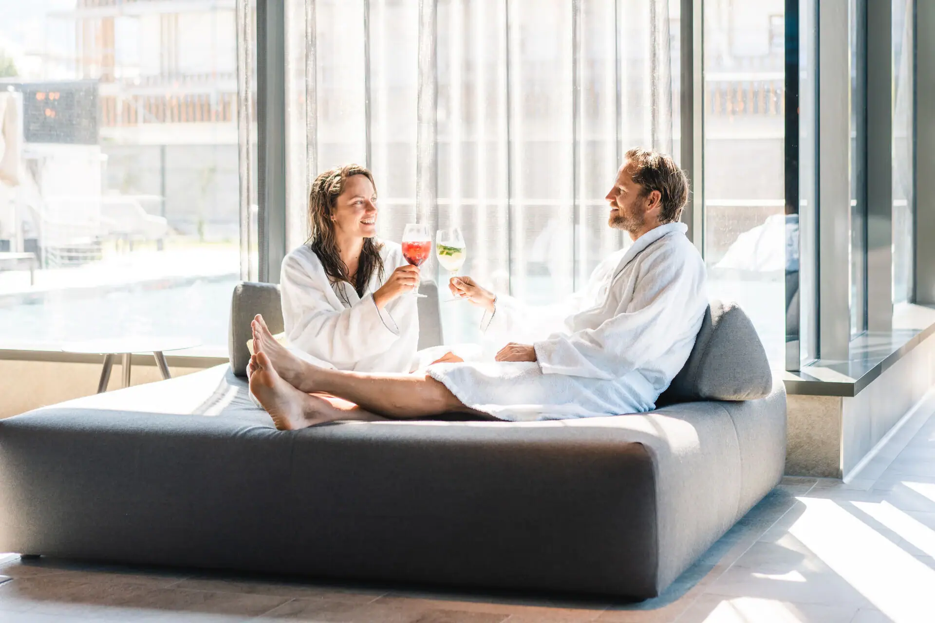 Een man en een vrouw in badjassen zitten op een bank.