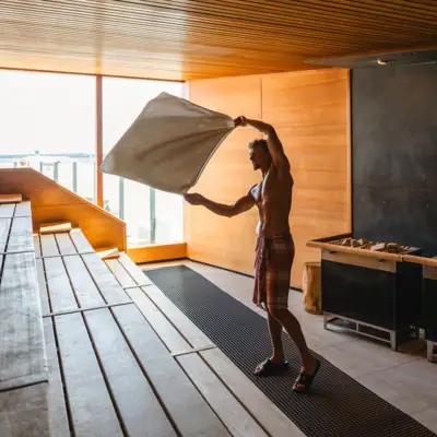 Een man houdt een handdoek vast in een sauna en geeft een sauna-infuus.