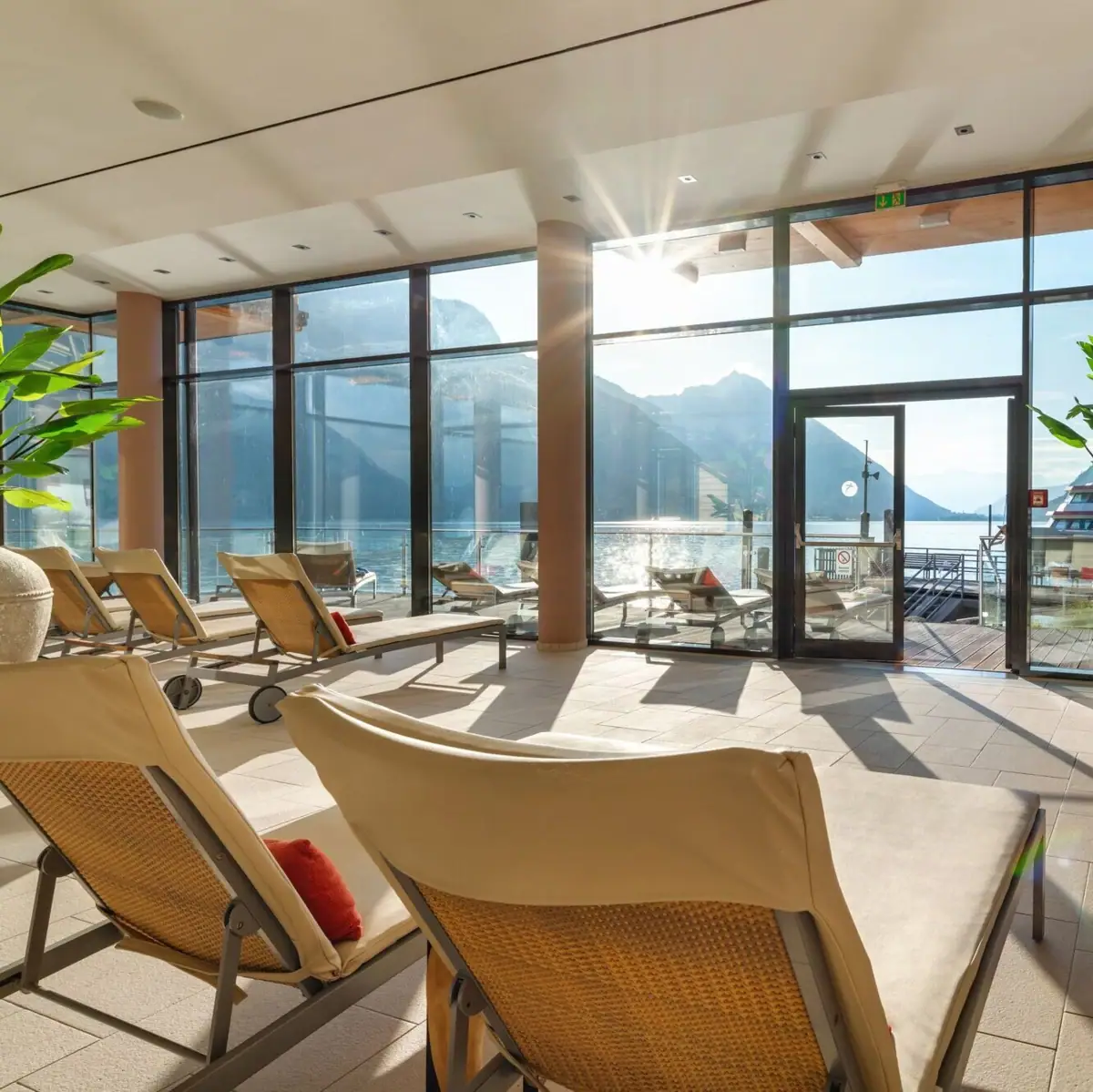 Een kamer met stoelen en een grote glazen deur.